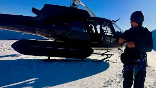 Black helicopter with skid landing gear parked on snow-covered ground