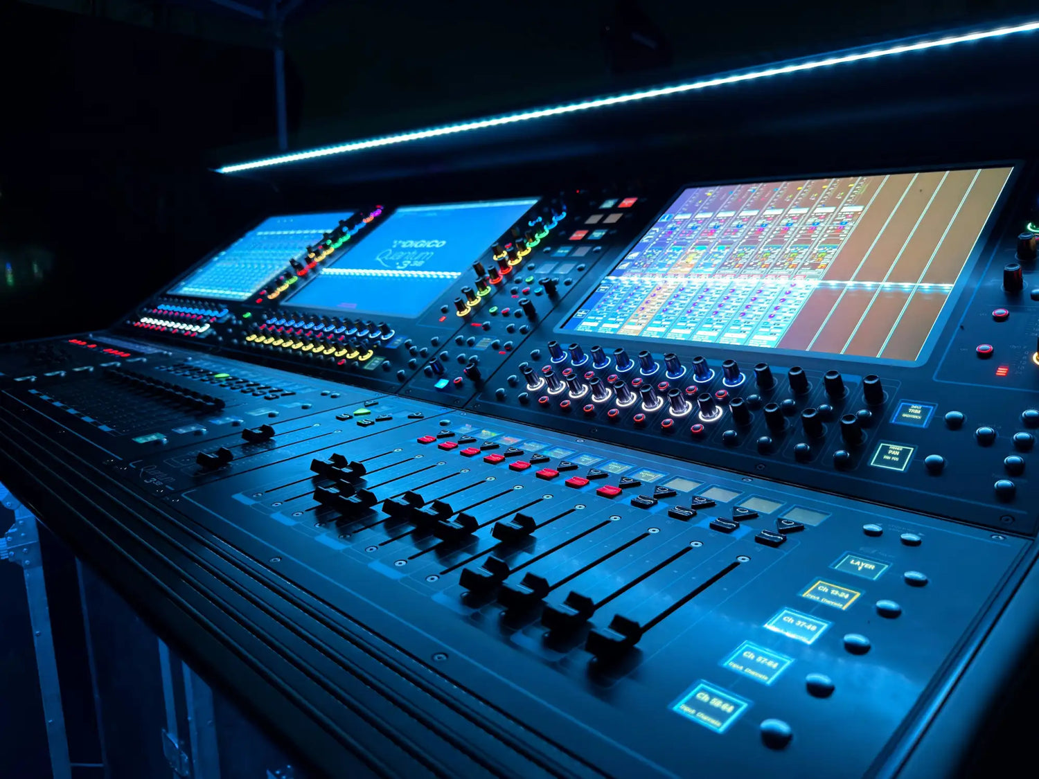 Black professional audio mixing console with illuminated blue screens and colorful control knobs.