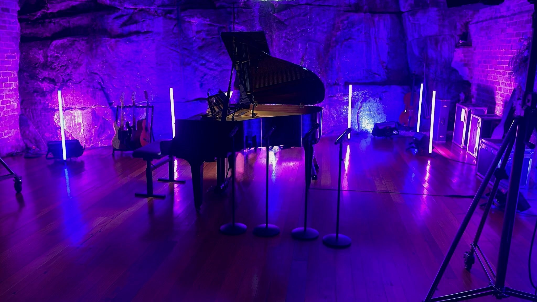 Grand piano on a stage with purple lighting and decorative elements.
