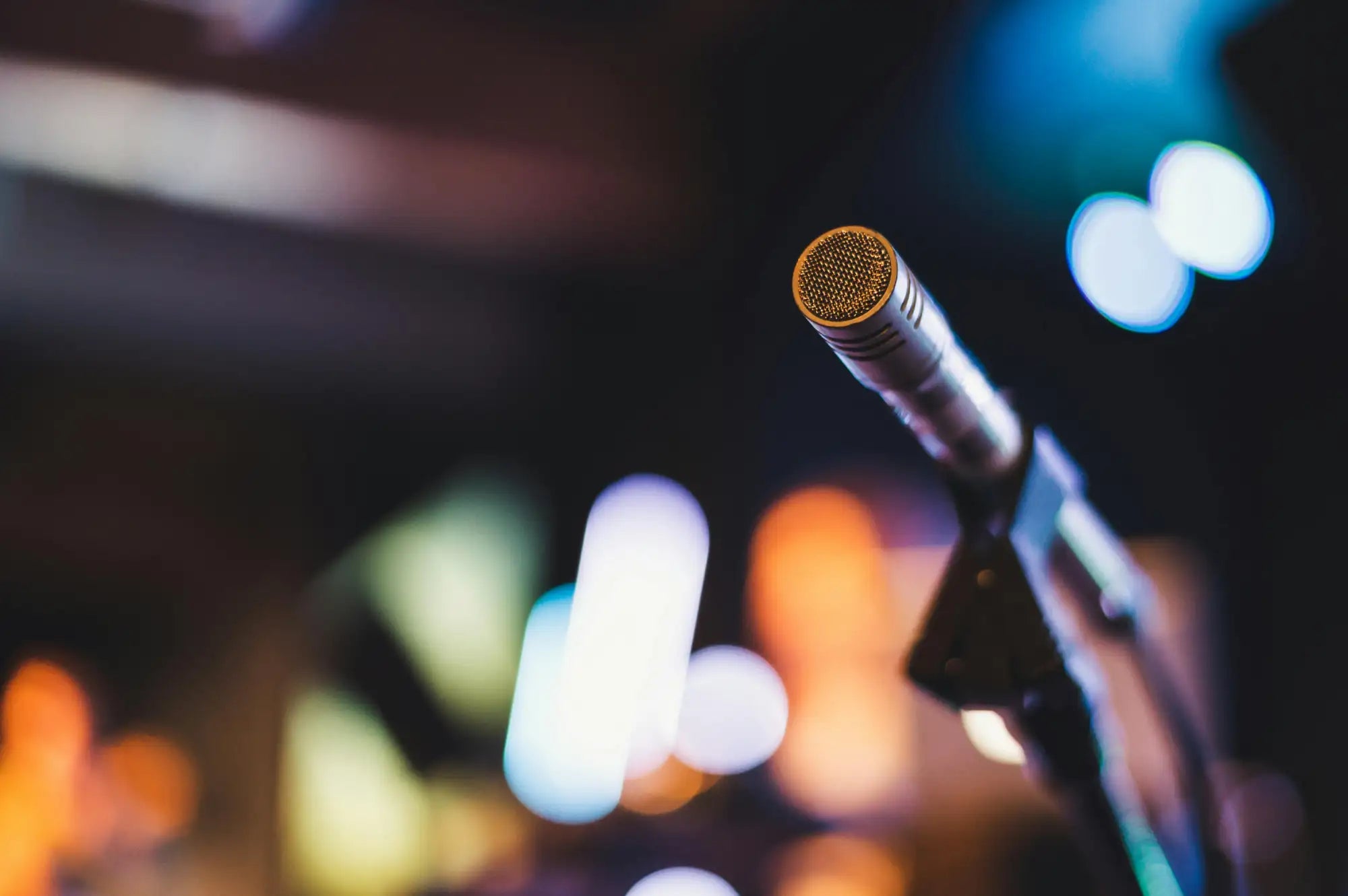 A sleek, gold-topped condenser microphone with a metallic body and mesh grille.